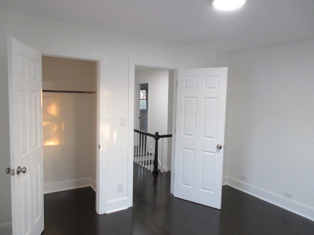 unfurnished bedroom with a closet and dark hardwood / wood-style flooring