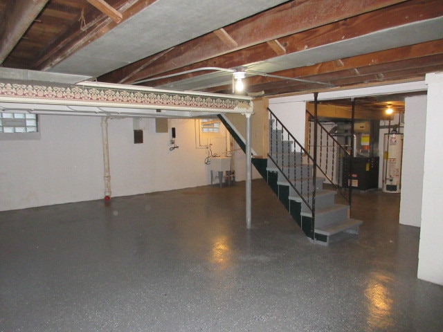 basement featuring gas water heater, heating unit, and sink