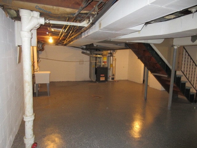 basement featuring gas water heater, sink, and heating unit