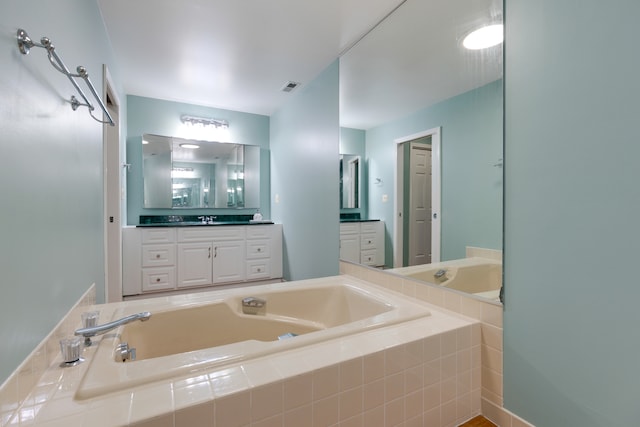 bathroom featuring vanity and tiled bath