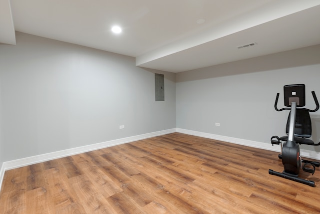 exercise room featuring electric panel and light wood-type flooring