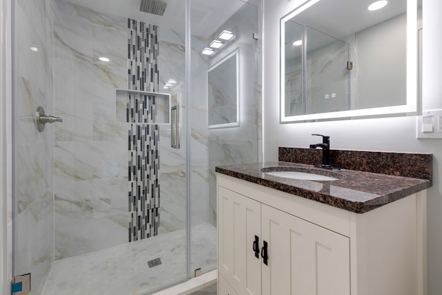 bathroom featuring a shower with shower door and vanity