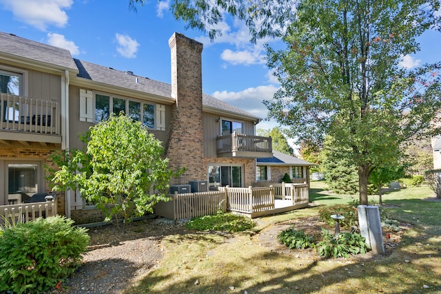 rear view of property with cooling unit and a balcony