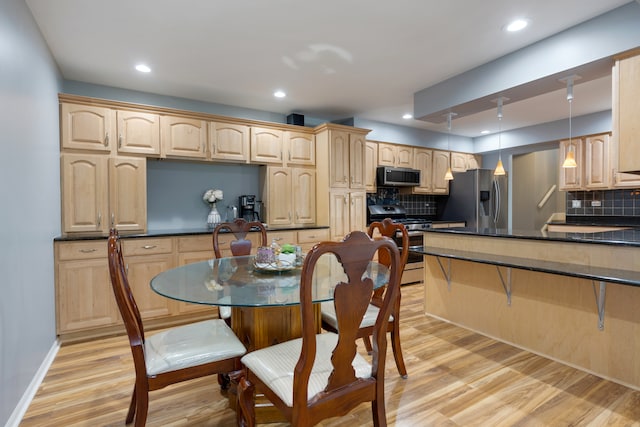 kitchen featuring appliances with stainless steel finishes, hanging light fixtures, light hardwood / wood-style floors, and tasteful backsplash