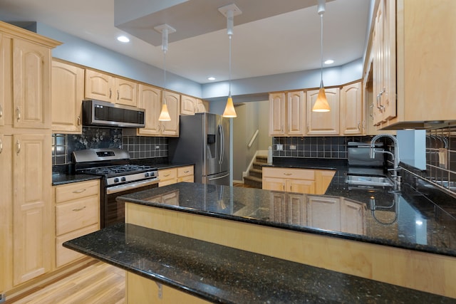 kitchen with pendant lighting, light hardwood / wood-style flooring, dark stone countertops, decorative backsplash, and appliances with stainless steel finishes