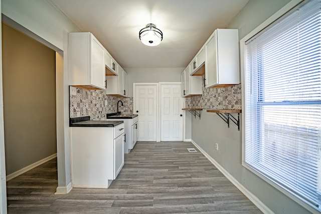 kitchen featuring decorative backsplash, light hardwood / wood-style floors, and white cabinetry