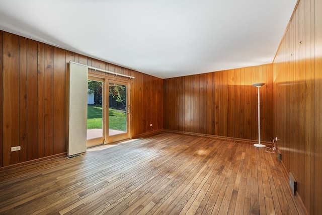 empty room with hardwood / wood-style flooring and wooden walls