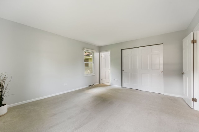 unfurnished bedroom featuring light carpet and a closet