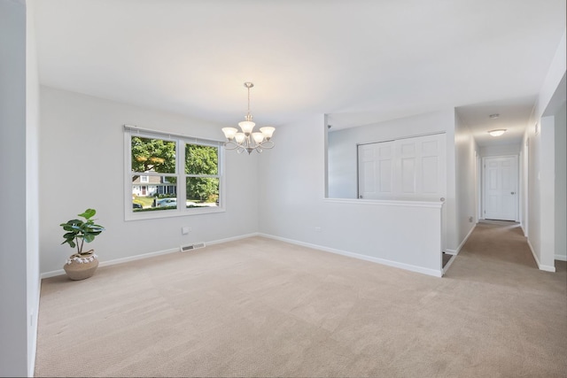 carpeted empty room featuring a notable chandelier