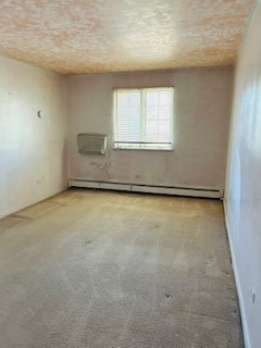 carpeted empty room featuring a textured ceiling and baseboard heating