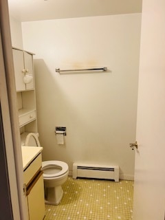 bathroom featuring toilet, a baseboard heating unit, vanity, and tile patterned floors