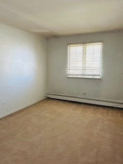 empty room with a baseboard heating unit and light colored carpet