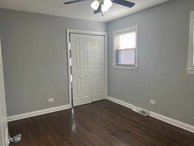 unfurnished bedroom with ceiling fan, dark hardwood / wood-style flooring, and a closet