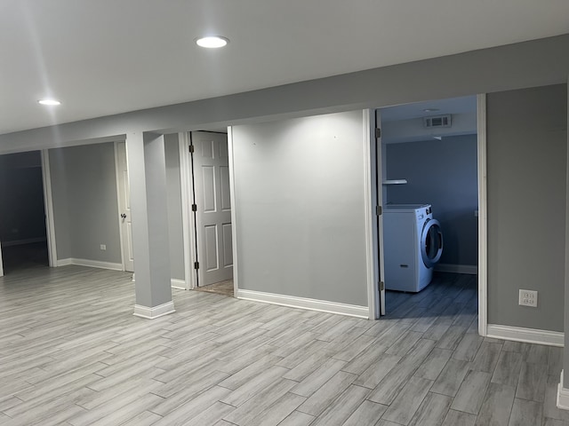 basement with washer / dryer and light hardwood / wood-style flooring