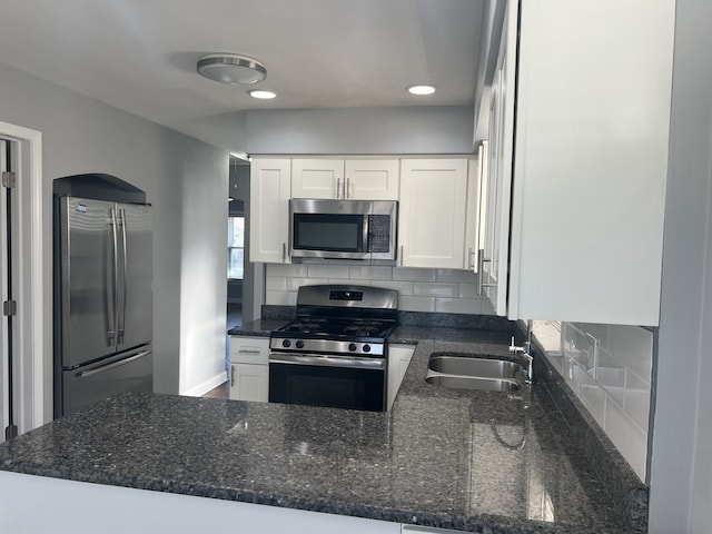 kitchen with appliances with stainless steel finishes, backsplash, white cabinetry, and sink