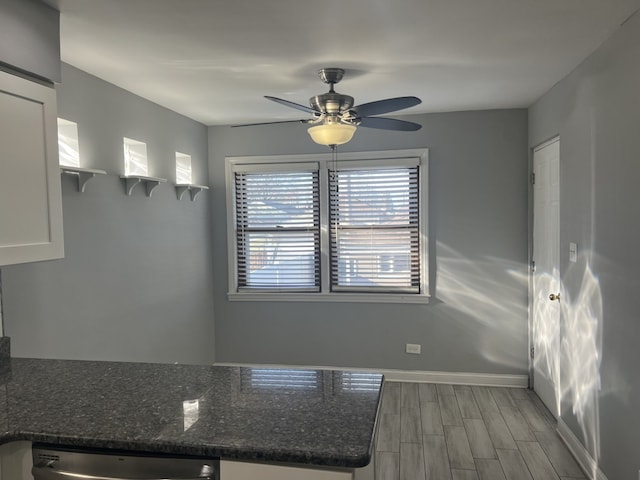 kitchen with light wood-type flooring, dark stone counters, ceiling fan, dishwasher, and white cabinets