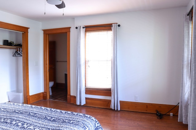 unfurnished bedroom featuring ceiling fan, a closet, ensuite bath, and dark wood-type flooring