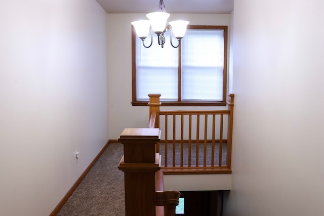 stairs with carpet floors and an inviting chandelier