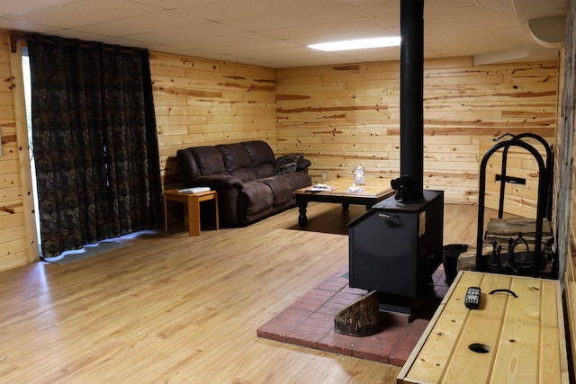 living room with wooden walls, a paneled ceiling, and hardwood / wood-style floors