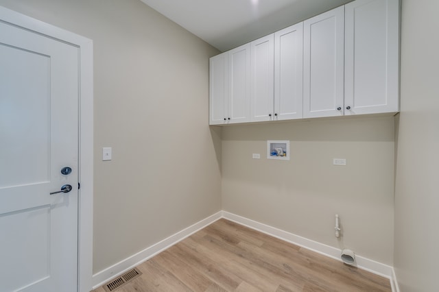 clothes washing area featuring hookup for a washing machine, cabinets, and light hardwood / wood-style flooring