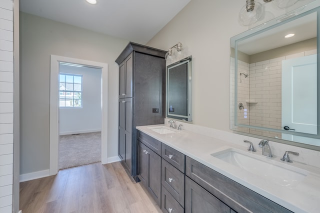 bathroom with hardwood / wood-style flooring, a tile shower, and vanity