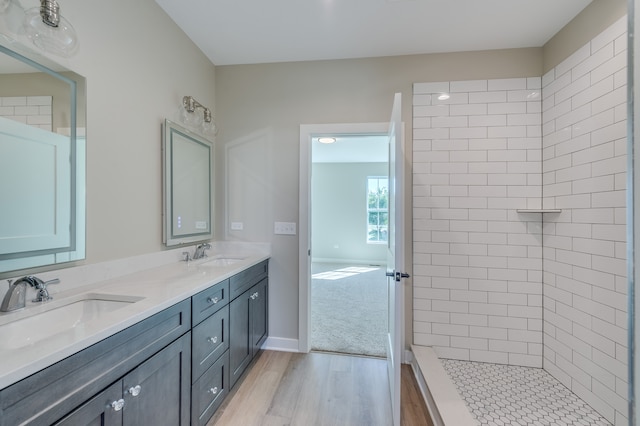 bathroom featuring wood-type flooring, a tile shower, and vanity