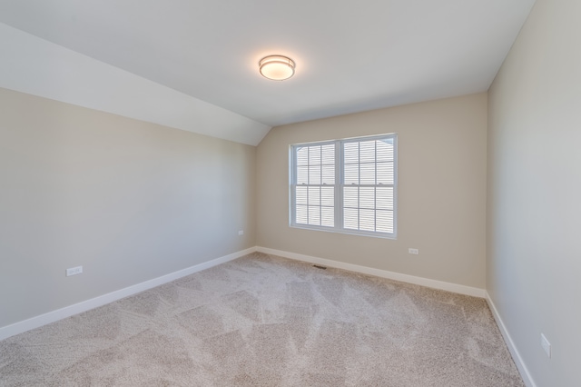 spare room with lofted ceiling and light carpet