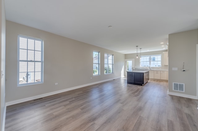 unfurnished living room with sink and light hardwood / wood-style floors