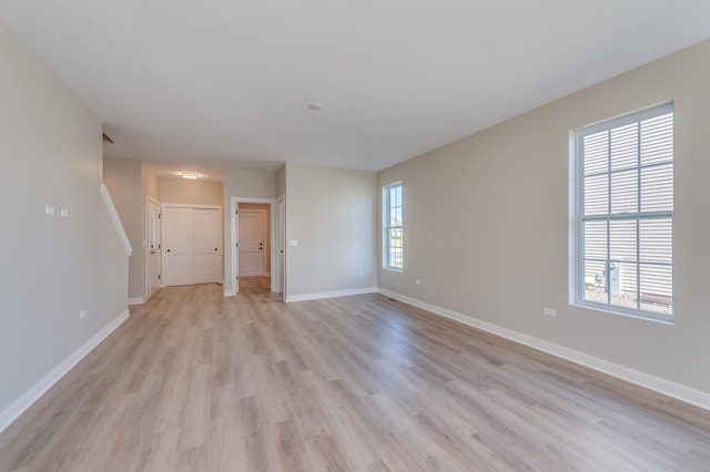 empty room with plenty of natural light and light hardwood / wood-style floors