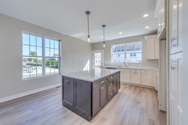 kitchen with hanging light fixtures, a kitchen island, dark brown cabinets, light hardwood / wood-style flooring, and white cabinetry