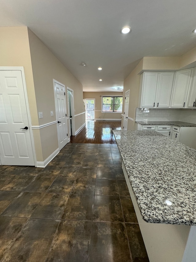 kitchen featuring light stone countertops, decorative backsplash, white cabinetry, and dark hardwood / wood-style flooring