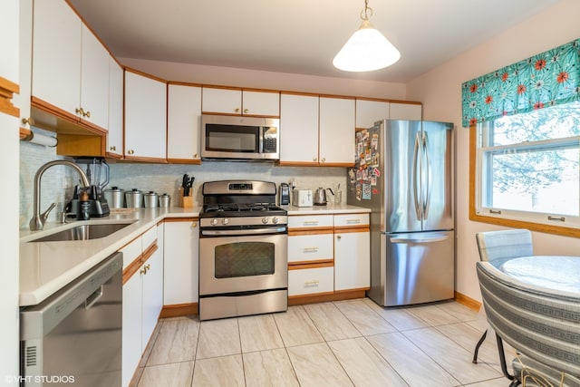 kitchen featuring white cabinets, sink, appliances with stainless steel finishes, decorative light fixtures, and backsplash