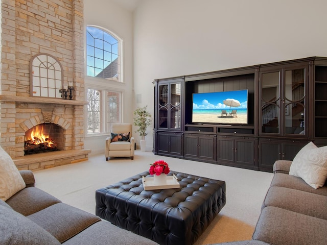 carpeted living room with a towering ceiling and a stone fireplace