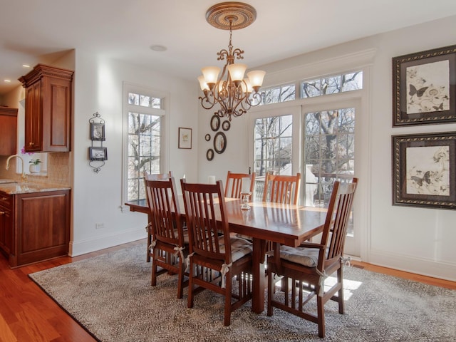 dining area featuring wood-type flooring, sink, and a notable chandelier