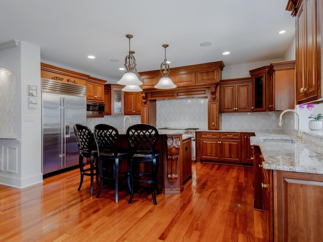 kitchen with dark hardwood / wood-style floors, built in appliances, sink, and a kitchen island