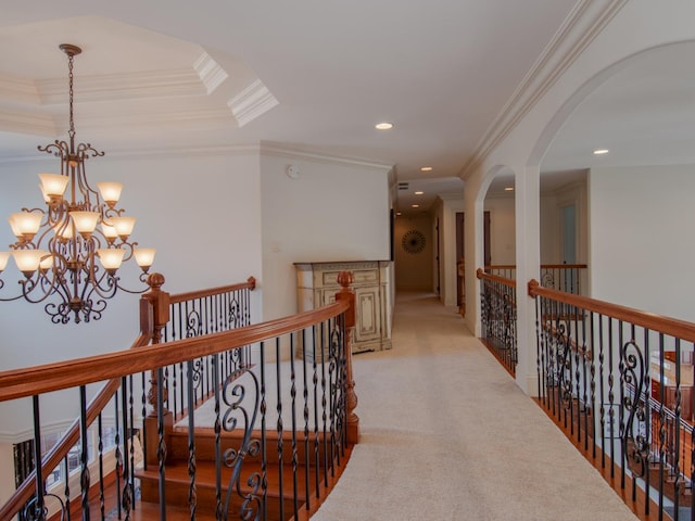 corridor featuring crown molding, a tray ceiling, a chandelier, and light carpet