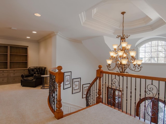 staircase with a raised ceiling, crown molding, carpet flooring, and a chandelier