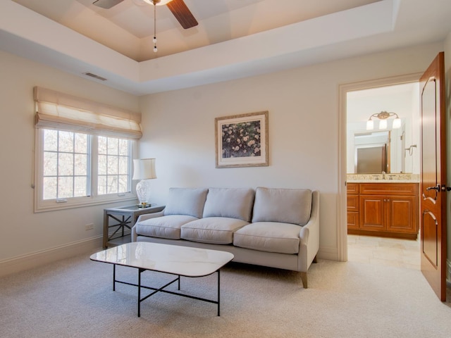 living room featuring a raised ceiling, sink, and light carpet