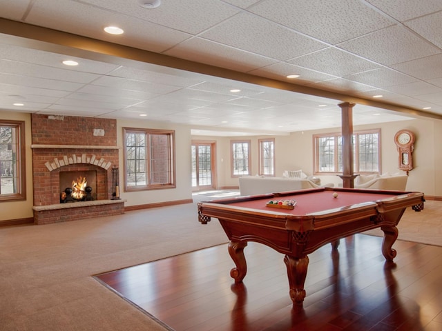 rec room with carpet flooring, a healthy amount of sunlight, a fireplace, and a drop ceiling