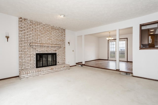 unfurnished living room featuring a fireplace, carpet, a textured ceiling, and an inviting chandelier