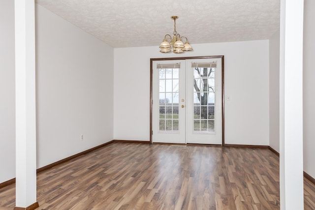 unfurnished room with dark wood-type flooring, french doors, a chandelier, and a textured ceiling