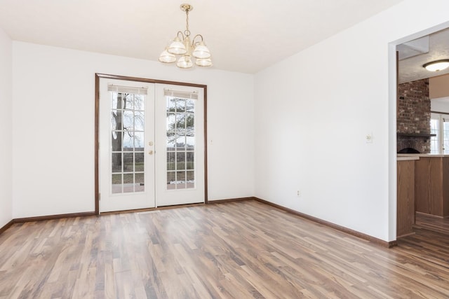 unfurnished dining area featuring french doors, light hardwood / wood-style floors, and an inviting chandelier