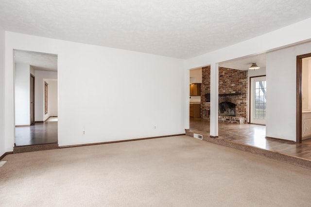 unfurnished living room with a textured ceiling, carpet floors, and a fireplace