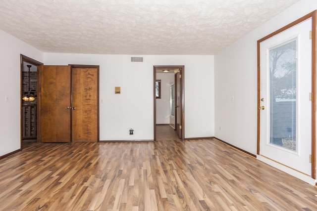 unfurnished bedroom featuring hardwood / wood-style floors, a textured ceiling, and a closet