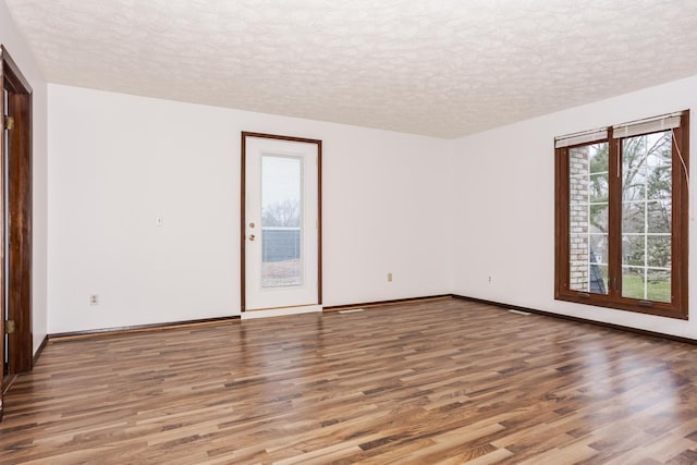 unfurnished room featuring wood-type flooring and a textured ceiling