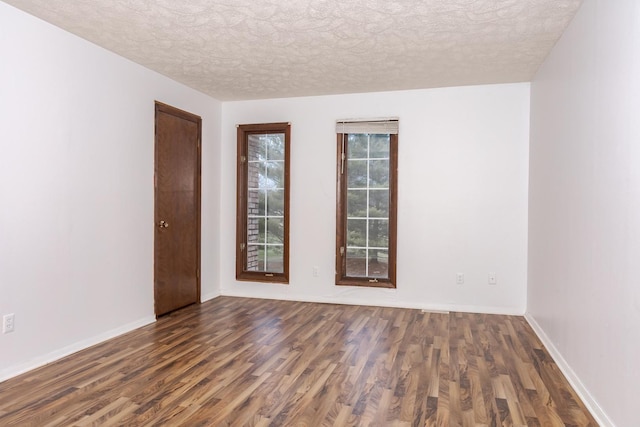 empty room with a textured ceiling, plenty of natural light, and dark wood-type flooring