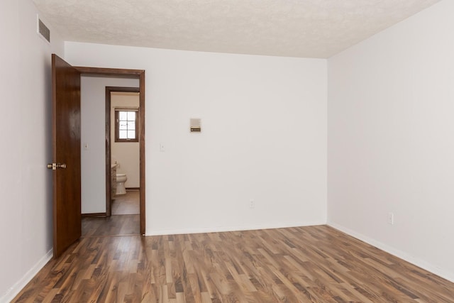 empty room featuring dark hardwood / wood-style flooring and a textured ceiling