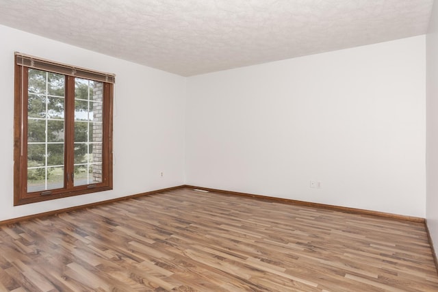 spare room featuring light hardwood / wood-style floors and a textured ceiling