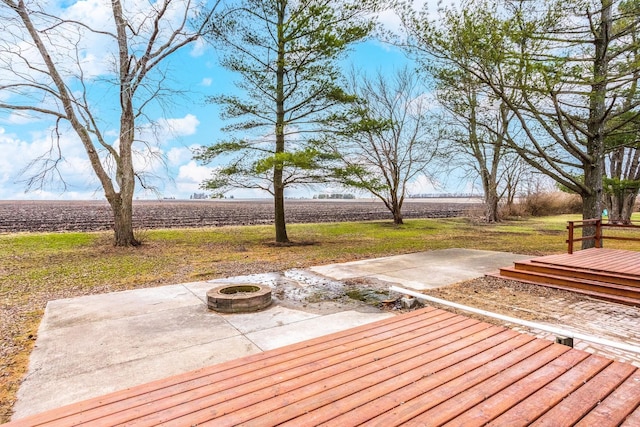 wooden terrace with a patio, a rural view, and an outdoor fire pit