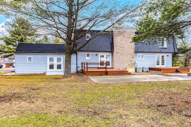 rear view of property with a lawn, a patio area, a wooden deck, and french doors